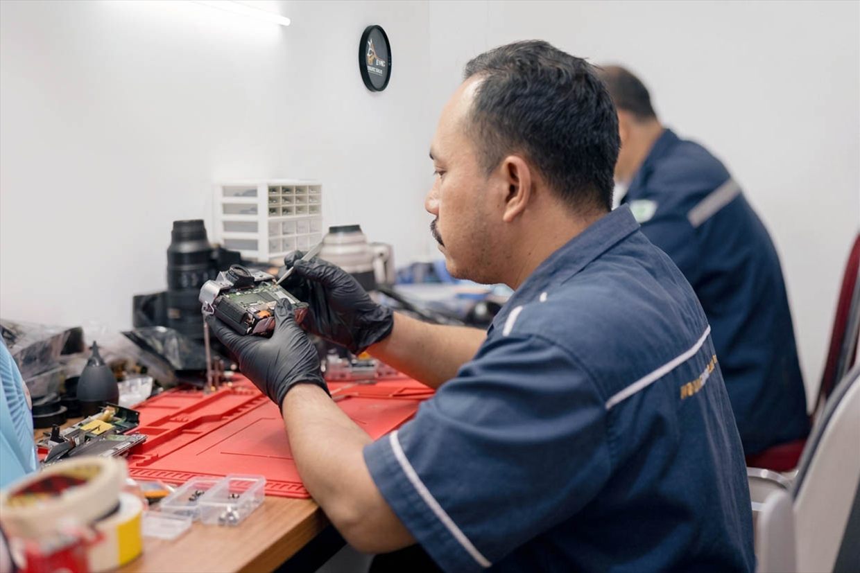 Teknisi YES Camera memeriksa mainboard kamera dengan pinset di meja servis
